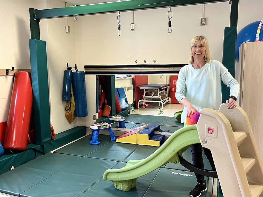 Kelli, Physiotherapist stands behind a children's plastic slide